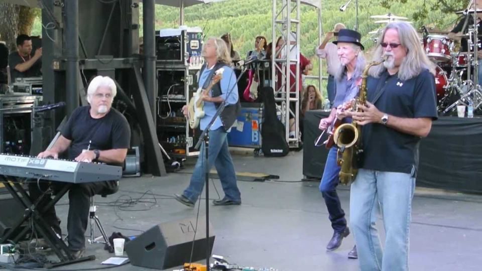 Michael McDonald at the keyboard with a saxophone player and guitarist beside him.